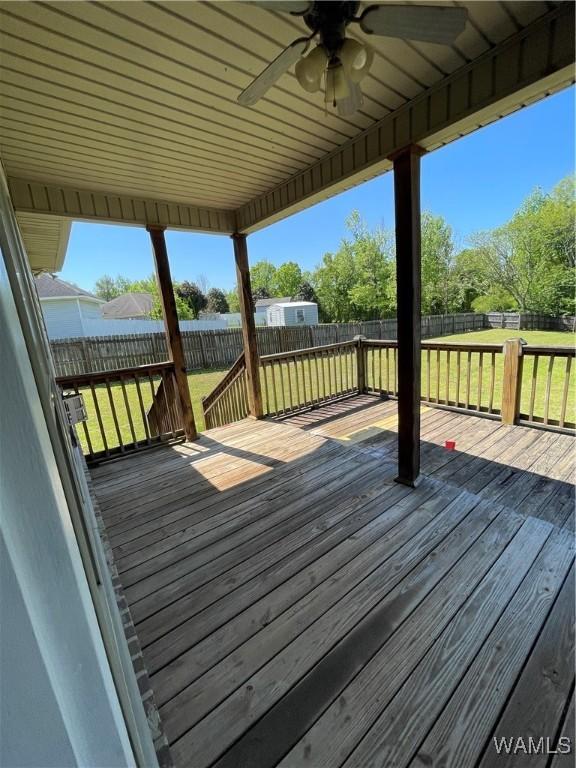 deck featuring a fenced backyard, ceiling fan, and a lawn