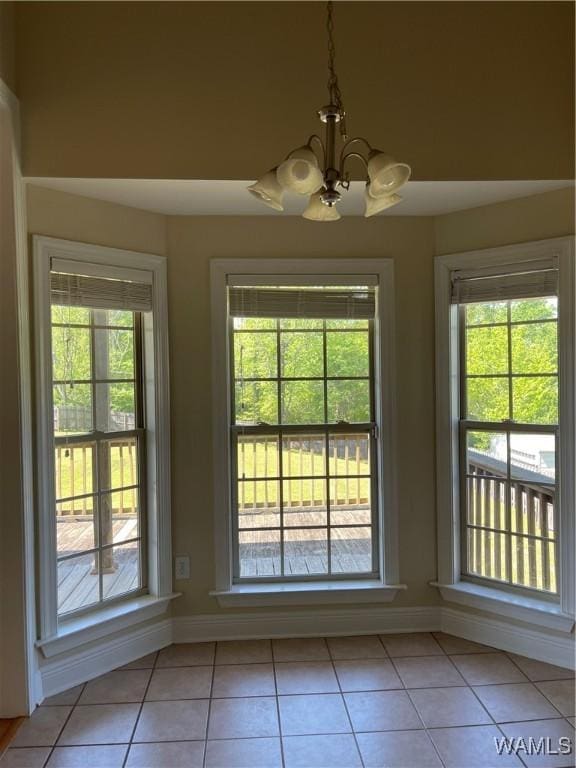 doorway to outside featuring an inviting chandelier, light tile patterned flooring, and a wealth of natural light