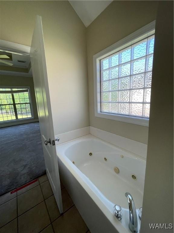 bathroom featuring lofted ceiling, a wealth of natural light, tile patterned flooring, and a jetted tub