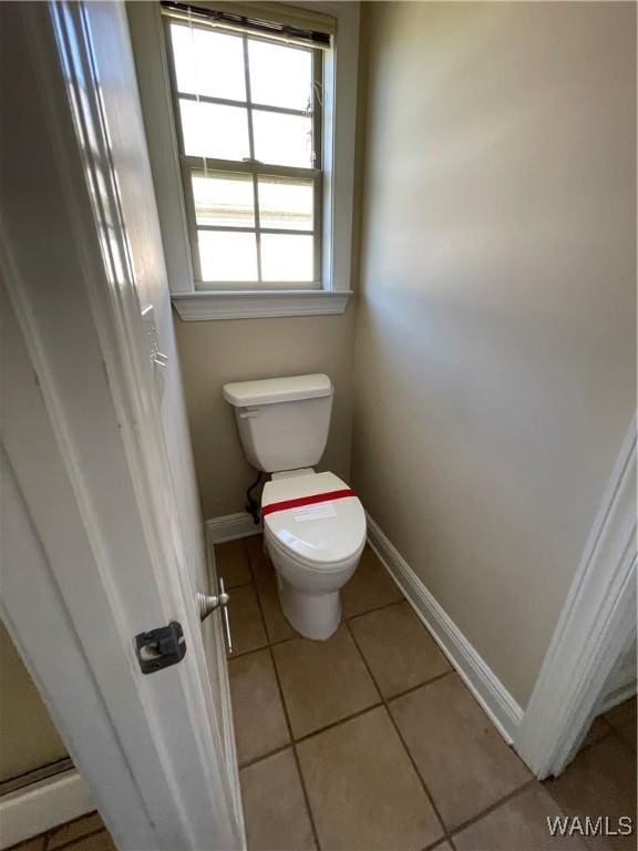 bathroom featuring tile patterned floors, baseboards, and toilet