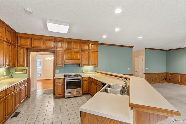 kitchen with light countertops, stainless steel gas range oven, a sink, and a peninsula