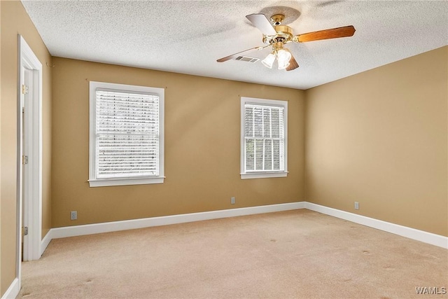 unfurnished room with baseboards, a textured ceiling, visible vents, a ceiling fan, and light carpet