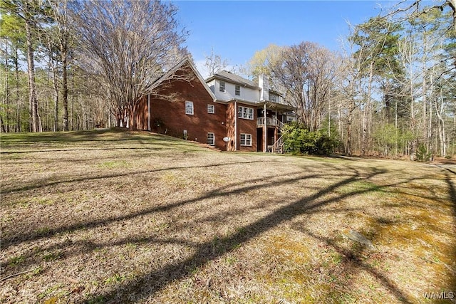 exterior space featuring a lawn, a chimney, stairway, and brick siding