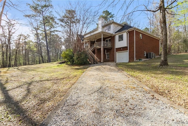 view of front of property featuring an attached garage, a chimney, central AC, stairs, and driveway