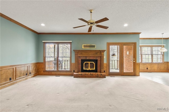 unfurnished living room featuring a wainscoted wall, a textured ceiling, and a healthy amount of sunlight