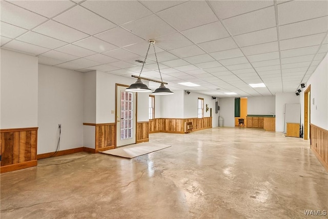 basement with a paneled ceiling, a wainscoted wall, wooden walls, and visible vents
