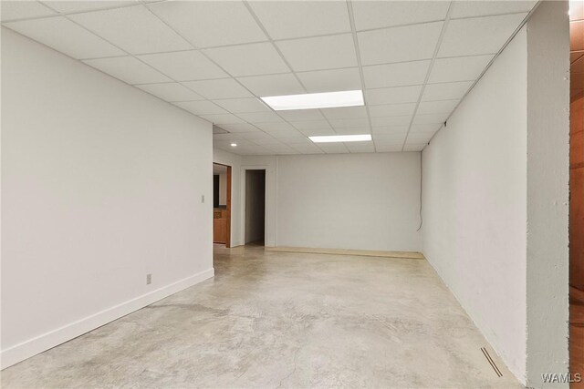 spare room with concrete flooring, baseboards, and a paneled ceiling