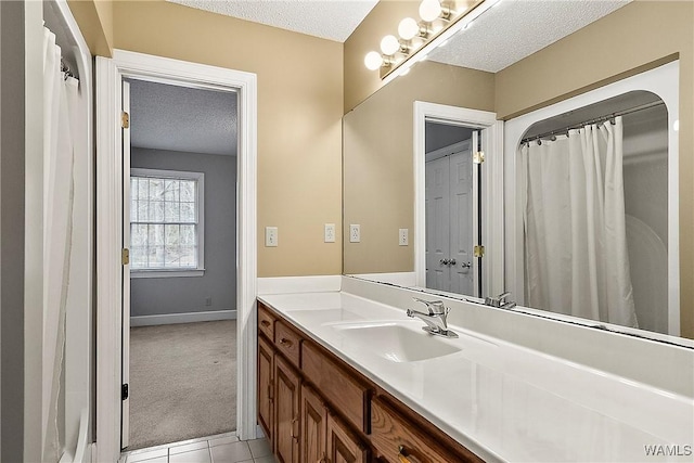 bathroom featuring tile patterned flooring, vanity, baseboards, and a textured ceiling
