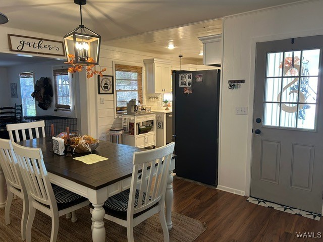 dining space with a notable chandelier, a healthy amount of sunlight, and dark hardwood / wood-style flooring