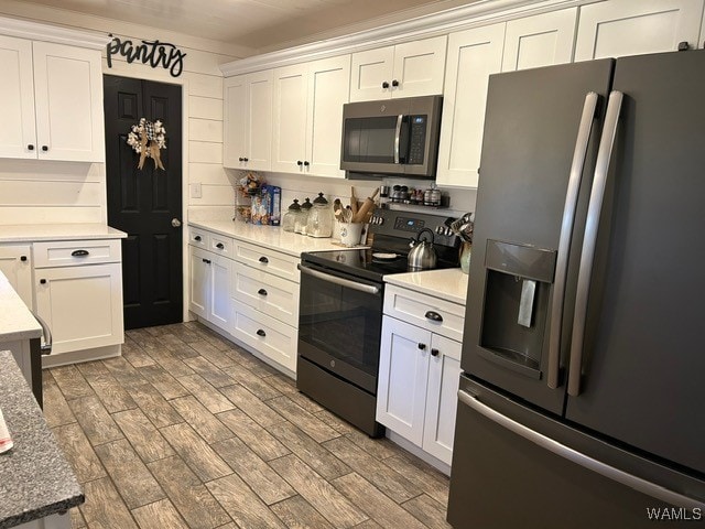 kitchen with white cabinets, wood-type flooring, and appliances with stainless steel finishes