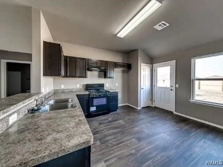 kitchen with sink, black gas stove, dark brown cabinets, light stone countertops, and dark hardwood / wood-style flooring