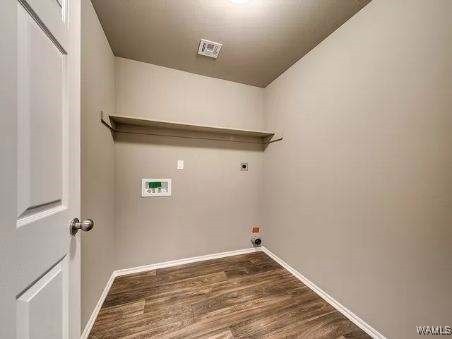 clothes washing area featuring electric dryer hookup and dark hardwood / wood-style flooring