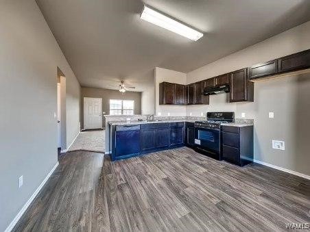 kitchen with dark hardwood / wood-style floors, black appliances, sink, kitchen peninsula, and dark brown cabinets