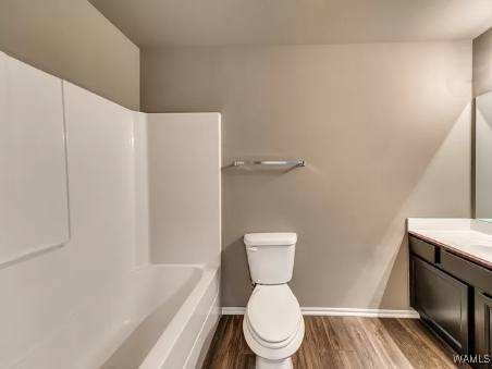 bathroom with vanity, a bathing tub, hardwood / wood-style floors, and toilet