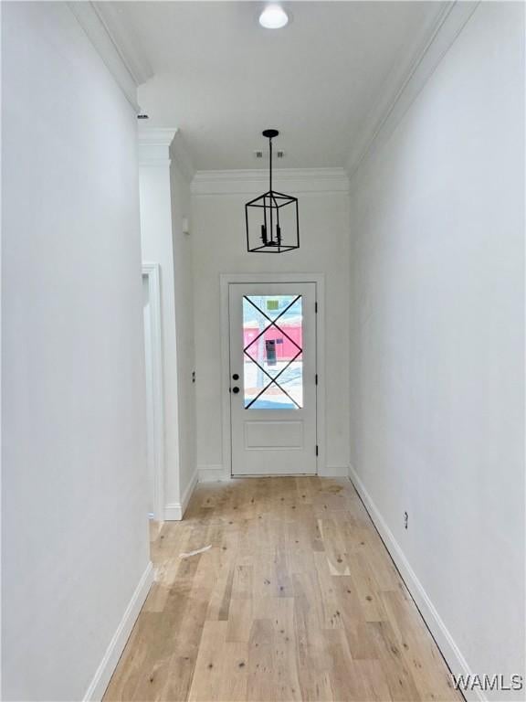 doorway to outside with baseboards, light wood finished floors, a notable chandelier, and crown molding