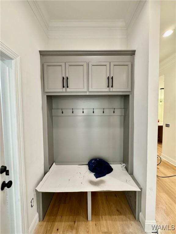 mudroom with light wood-type flooring, crown molding, and baseboards