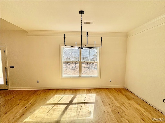 unfurnished dining area with ornamental molding, light wood-type flooring, visible vents, and baseboards