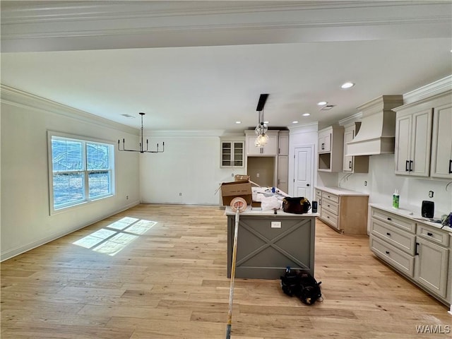 kitchen with light wood-style floors, a kitchen island, custom range hood, and ornamental molding