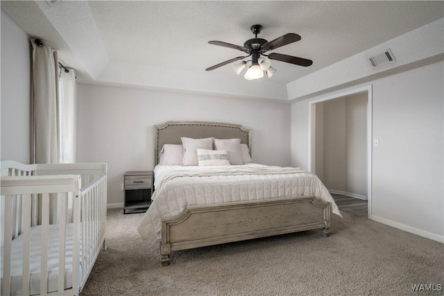 bedroom featuring ceiling fan, a tray ceiling, carpet floors, and a textured ceiling