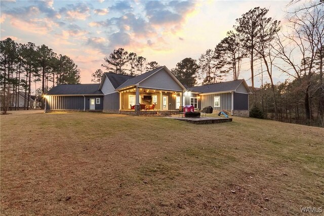 10649 Legacy Point Dr, Northport, AL 35475 - back of property at dusk with board and batten siding, a yard, and a patio
