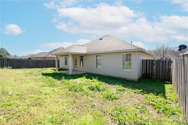 rear view of house with a fenced backyard, a lawn, and a patio