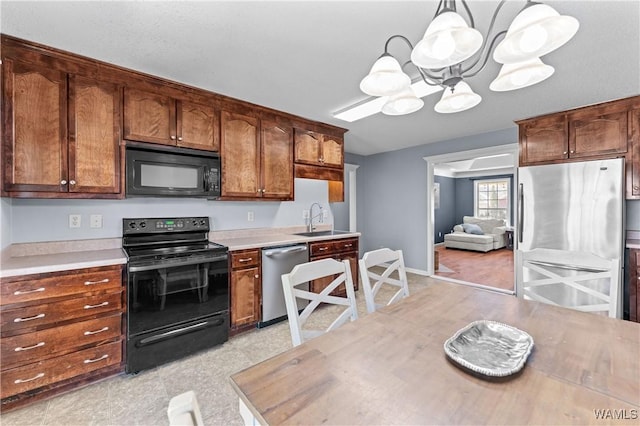 kitchen with light countertops, an inviting chandelier, hanging light fixtures, black appliances, and a sink