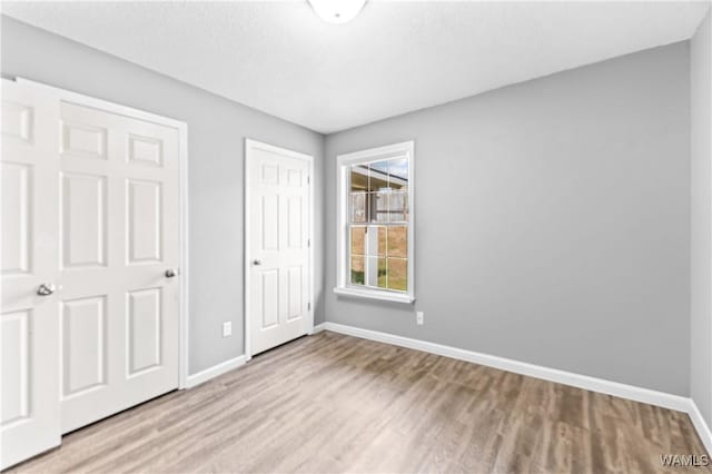 unfurnished bedroom featuring a closet, baseboards, and wood finished floors