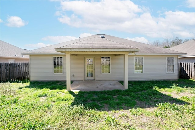 rear view of property featuring a yard, a patio, and a fenced backyard