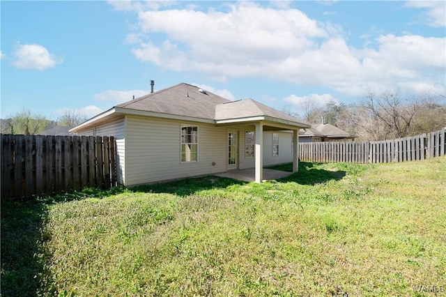 back of property with a fenced backyard, a lawn, and a patio