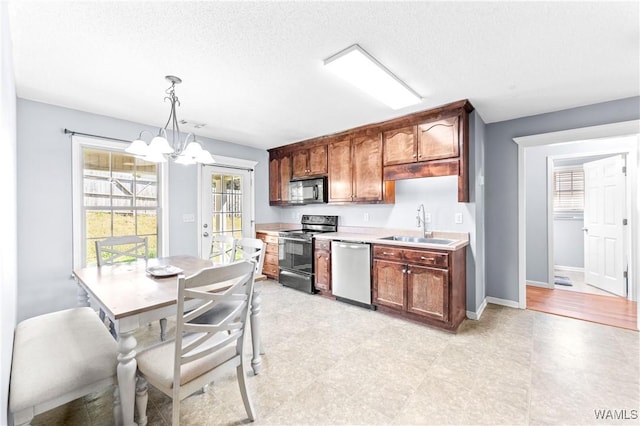 kitchen with a sink, black appliances, light countertops, decorative light fixtures, and a notable chandelier