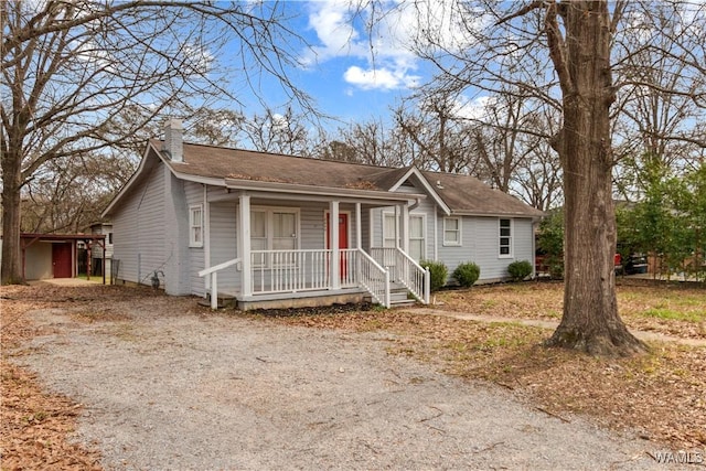 ranch-style house featuring covered porch, driveway, and a chimney