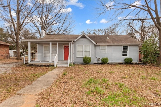 ranch-style home featuring covered porch, a chimney, and fence