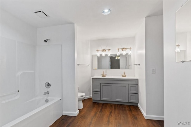 full bath featuring bathtub / shower combination, toilet, wood finished floors, vanity, and visible vents