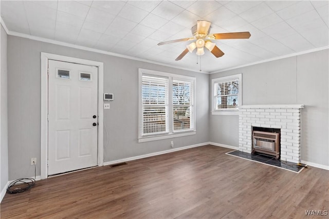 unfurnished living room featuring ceiling fan, a fireplace, wood finished floors, visible vents, and crown molding