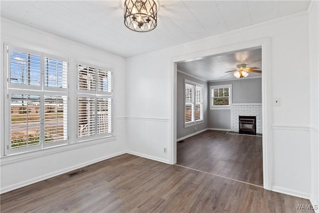 interior space featuring a fireplace, wood finished floors, visible vents, a ceiling fan, and crown molding