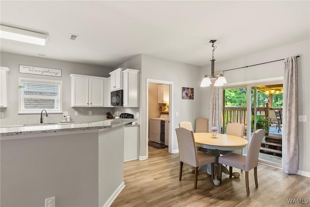 2757 Lily Cir, Northport, AL 35473 - kitchen featuring black microwave, washing machine and dryer, white cabinets, and light wood-style floors