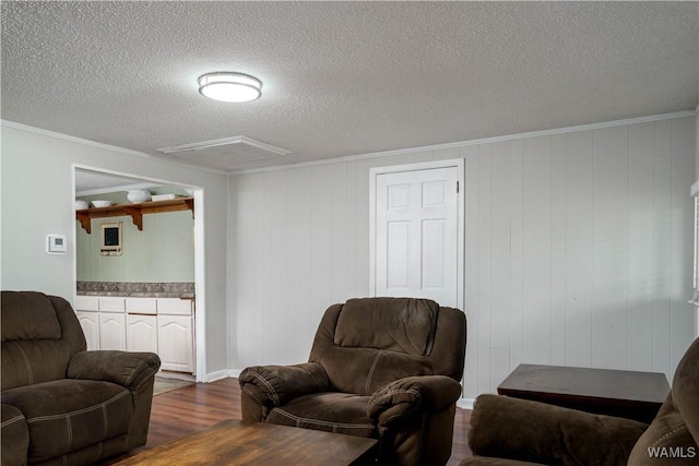 living area with a textured ceiling, dark wood finished floors, and ornamental molding