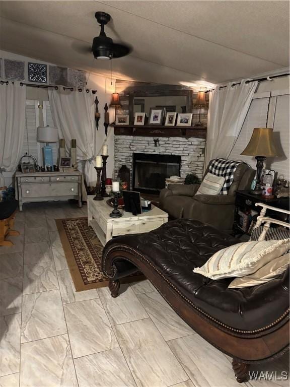 living area with a fireplace, ceiling fan, and marble look tile flooring