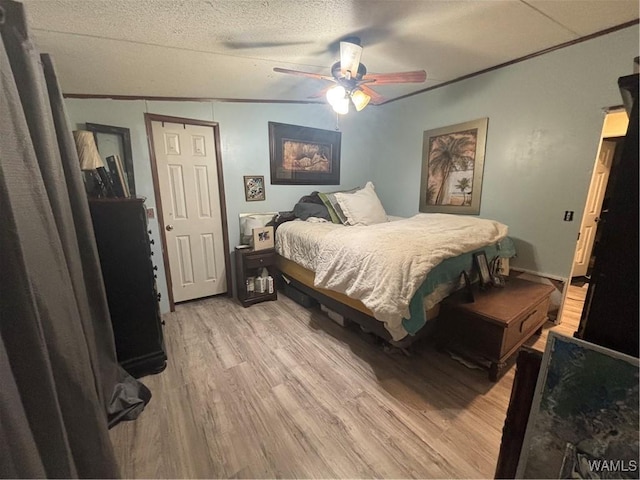 bedroom with light wood-style floors, ornamental molding, ceiling fan, and a textured ceiling