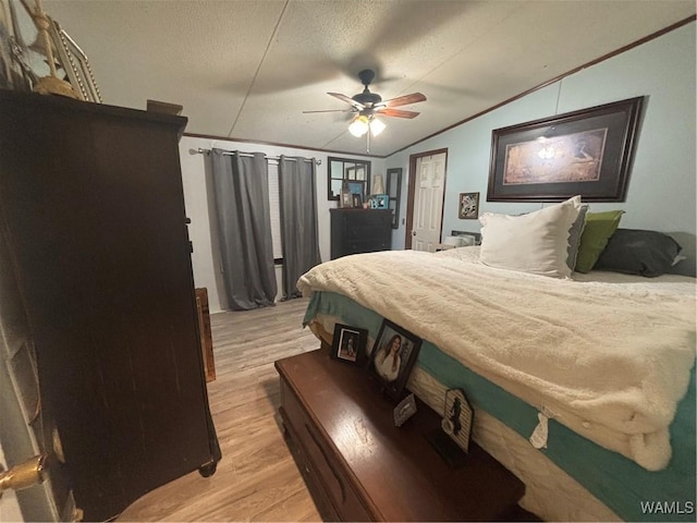 bedroom with vaulted ceiling, light wood-style floors, crown molding, a ceiling fan, and a textured ceiling
