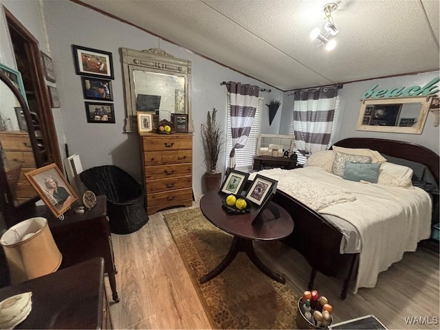 bedroom with vaulted ceiling, light wood-style flooring, and a textured ceiling
