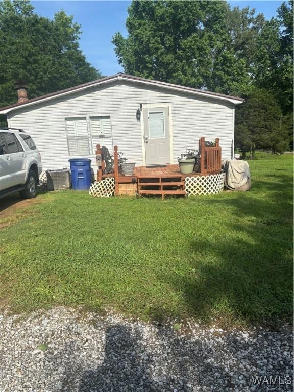 rear view of property featuring a wooden deck and a yard