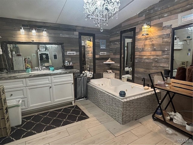 full bath featuring wooden walls, vaulted ceiling, a whirlpool tub, vanity, and a chandelier
