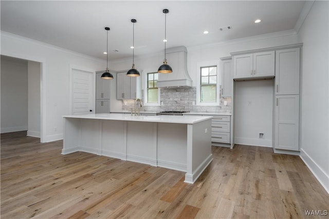 407 Edgefield Mews Cir, Tuscaloosa, AL 35406 - kitchen featuring custom exhaust hood, light countertops, decorative backsplash, an island with sink, and crown molding