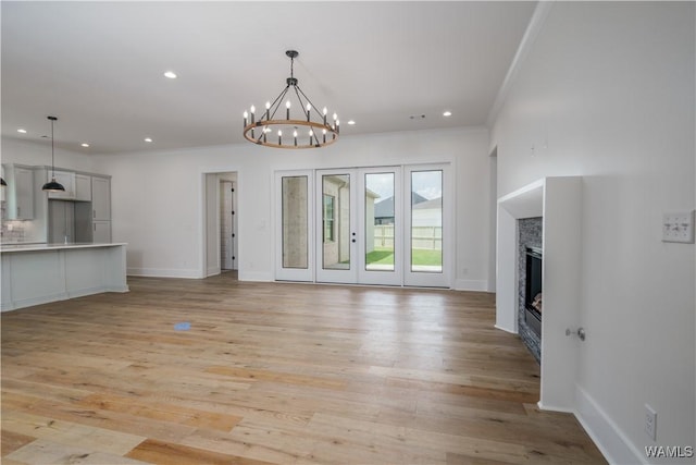 407 Edgefield Mews Cir, Tuscaloosa, AL 35406 - unfurnished living room featuring recessed lighting, crown molding, light wood-style floors, a glass covered fireplace, and a chandelier