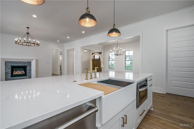 407 Edgefield Mews Cir, Tuscaloosa, AL 35406 - kitchen with a chandelier, open floor plan, wood finished floors, decorative light fixtures, and white cabinetry