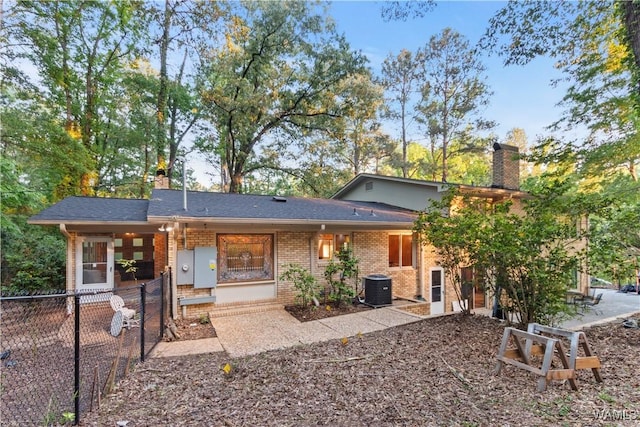 back of property with brick siding, fence, a chimney, and cooling unit