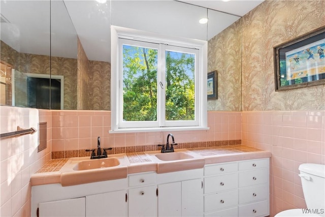 4704 Oneida Ave, Northport, AL 35473 - full bath with wallpapered walls, tile walls, toilet, double vanity, and a wainscoted wall
