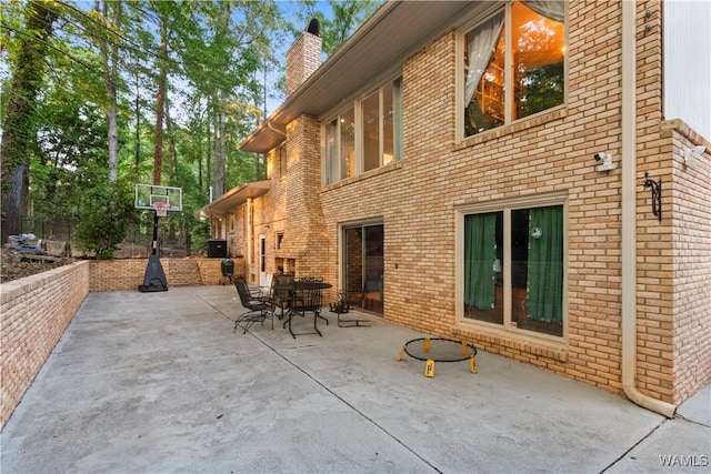 rear view of property featuring a chimney, a patio area, and brick siding