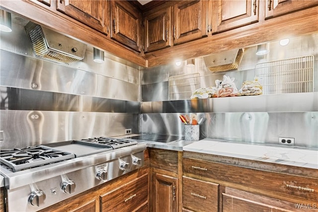 4704 Oneida Ave, Northport, AL 35473 - kitchen featuring stainless steel gas cooktop, decorative backsplash, brown cabinets, and light stone counters